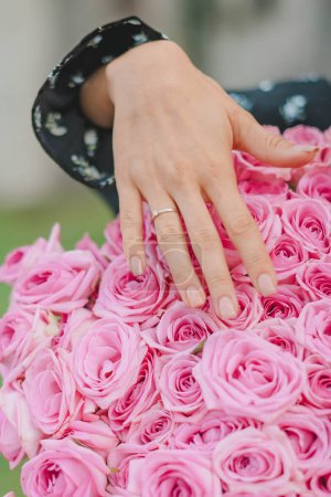 Photo for Close up of an elegant diamond ring on woman finger with white flower, sunlight and shadow background. engagement, love and wedding concept. selective focus. - Royalty Free Image