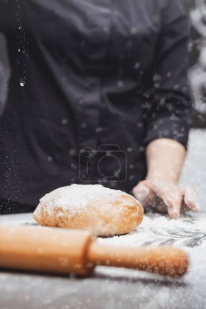Photo for An experienced chef cooks in a professional kitchen prepares dough with flour for making ciabatta bread. - Royalty Free Image