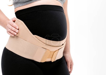 Pregnant woman belly in prenatal pregnancy maternity belt. Orthopedic abdominal support waist, back, abdomen band. Belly brace or band for pregnancy. Horizontal web banner. Torso of pregnant model isolated on white background.