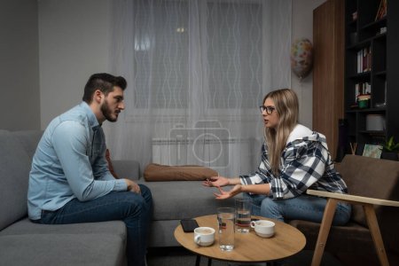 Young married couple husband and wife sitting at home having problems in their marriage and a cold relationship. A boyfriend and a girlfriend have an argument about spending too much money.