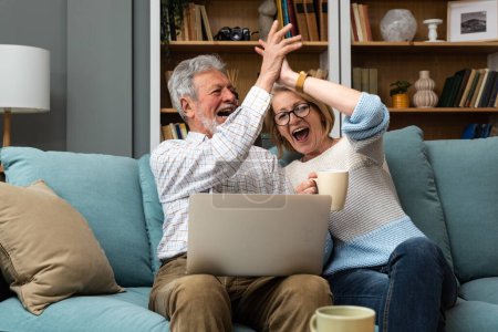 Photo for Excited senior mature couple surprised by good unbelievable news, unexpected win, huge shopping sale offer on website, astonished older middle aged family looking at computer screen feeling amazed - Royalty Free Image