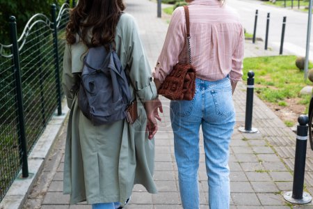 Téléchargez les photos : Deux femmes marchant dans la rue, une de son portefeuille tombe de sa poche de manteau, elle ne remarque pas. Concept de portefeuille perdu. - en image libre de droit
