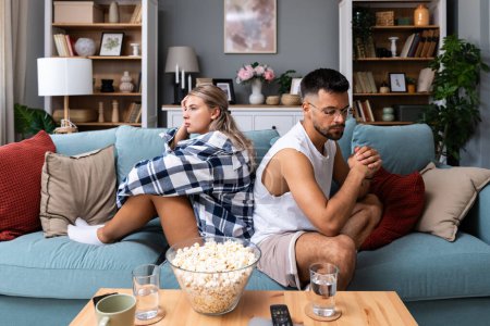 Photo for Stressed young married couple sitting separately on different sides of sofa ignoring each other after quarrel. Offended spouses not talk communicate feeling depressed disappointed after argue. - Royalty Free Image