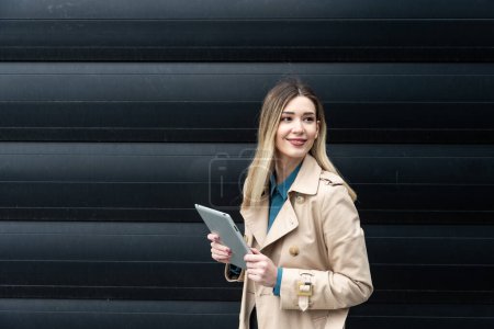 Photo for Portrait of young confident successful business woman standing outside office building. Educated independent female team leader businessperson posing against black wall. - Royalty Free Image