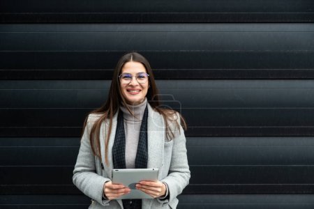 Photo for Portrait of young confident successful business woman standing outside office building. Educated independent female team leader businessperson posing against black wall. - Royalty Free Image