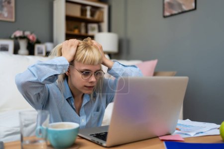 Computer bug. Young nervous frustrated freelance woman in home office having trouble with laptop or internet connection Anxious and angry university student college girl worried about educational exam