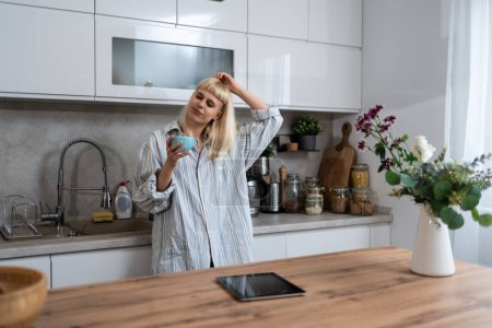 Junge Frau morgens in der häuslichen Küche in ihrer Wohnung mit dem ersten Kaffee, um aufzuwachen, bevor sie zur Arbeit geht. Lebensstil erfolgreicher unabhängiger Jobinhaber.