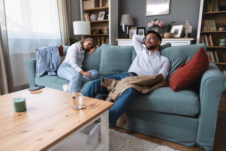 Tired man and woman sitting at home from work after hard working day at business company. Couple relaxing on sofa after job interview