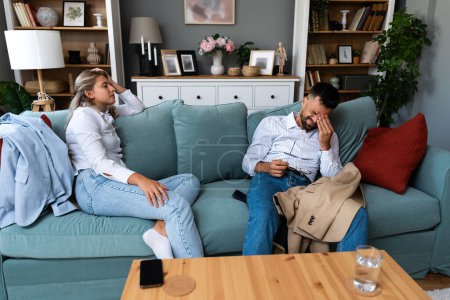 Tired man and woman sitting at home from work after hard working day at business company. Couple relaxing on sofa after job interview