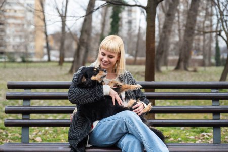Das Hipstermädchen der jungen Generation Z sitzt im Park auf einer Bank mit ihrem Adoptivhund, den sie vor dem Hungertod gerettet hat, und schenkt ihm Liebe und Aufmerksamkeit. Tierliebhaber genießen mit ihrem Haustier.