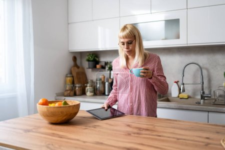 Morning routine. Young freelance businesswoman, designer professional, small business owner, startup company foreperson, drinking coffee in domestic kitchen before she go to the work.