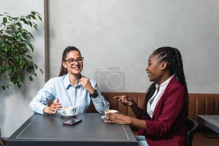 Zwei junge Geschäftsfrauen, Büroangestellte und beste Freundinnen, die eine Kaffeepause in der Cafeteria einlegen Inhaber von Kleinunternehmen sitzen im Café und genießen ihren Erfolg und ihren Verdienst