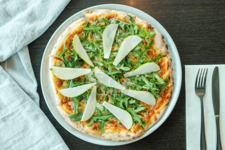 Photo for Pizza with rocket and pear on a wooden table, close up - Royalty Free Image