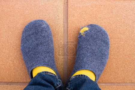 Photo for Poor man wearing worn, torn and widely used house slippers showing his toe. Concept of poverty, low salary, job loss, economic and energy crisis. - Royalty Free Image