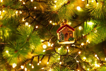 Photo for Close up of Christmas tree decoration with lights. Delicate Christmas ornament depicting a cozy little house, evoking the warmth and magic of festive holiday nights. - Royalty Free Image