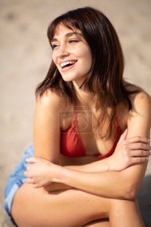 Foto de Retrato de cerca de una joven feliz sentada en la playa de arena en un día de verano - Imagen libre de derechos