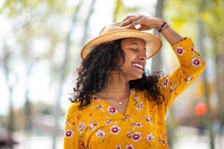 Téléchargez les photos : Portrait de belle jeune femme africaine avec chapeau debout à l'extérieur - en image libre de droit