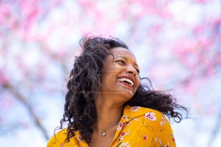 Foto de Retrato de cerca de una hermosa joven latina en el parque en primavera mirando hacia otro lado y sonriendo - Imagen libre de derechos