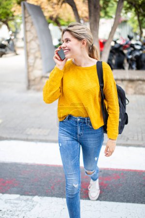 Photo for Portrait of cheerful young latin woman walking outside talking on cellphone - Royalty Free Image