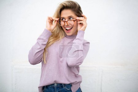Foto de Retrato de una hermosa joven sonriendo con gafas contra la pared blanca - Imagen libre de derechos