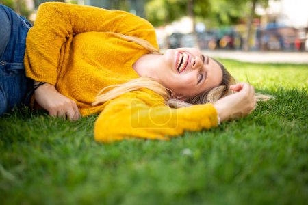 Foto de Primer plano retrato de la joven alegre tumbada en la hierba y riendo - Imagen libre de derechos