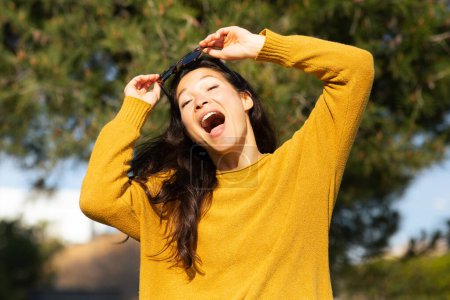 Téléchargez les photos : Portrait de jeune femme chinoise excitée debout dehors regardant la caméra et riant - en image libre de droit