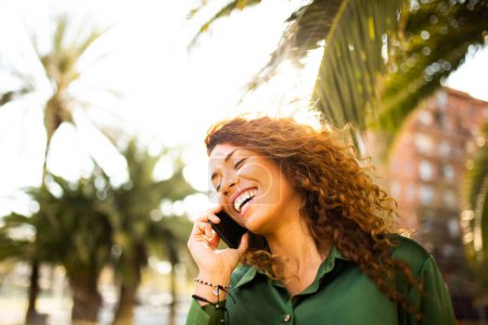 Photo for Closeup portrait of cheerful young woman making a phone call outdoors in the city - Royalty Free Image