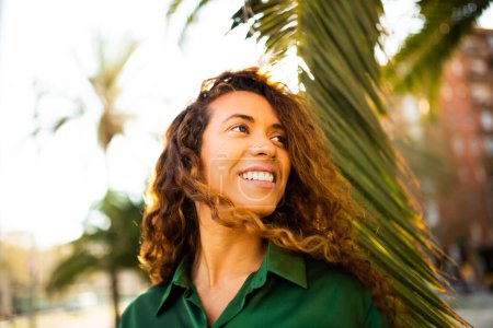 Foto de Retrato de cerca de una hermosa joven latina mirando hacia otro lado y sonriendo afuera - Imagen libre de derechos