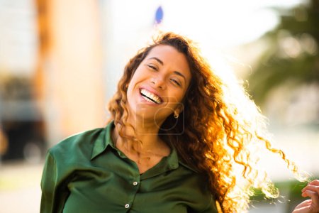 Foto de Primer plano retrato de una hermosa joven latina con cabello castaño mirando a la cámara y sonriendo afuera en un día de verano - Imagen libre de derechos