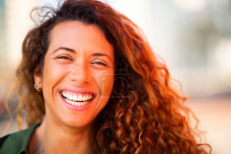 Photo for Close up portrait of smiling young hispanic woman looking at camera and laughing outside - Royalty Free Image