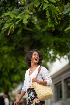 Téléchargez les photos : Portrait jeune femme avec sac à main souriant à l'extérieur - en image libre de droit