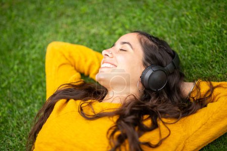 Téléchargez les photos : Gros plan portrait d'une jeune femme souriante écoutant de la musique avec des écouteurs - en image libre de droit