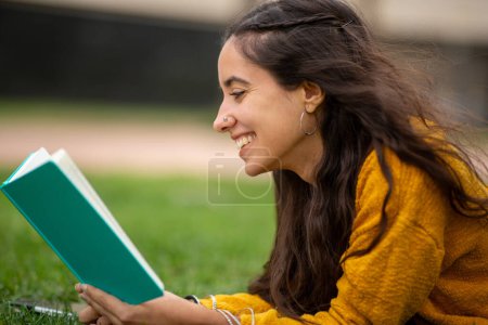 Foto de Retrato de cerca de una joven sonriente leyendo un libro - Imagen libre de derechos