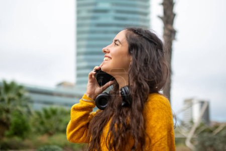 Téléchargez les photos : Portrait latéral rapproché d'une jeune femme souriante parlant avec un téléphone portable - en image libre de droit