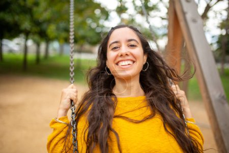 Téléchargez les photos : Gros plan portrait de jeune femme heureuse sur swing dans le parc - en image libre de droit