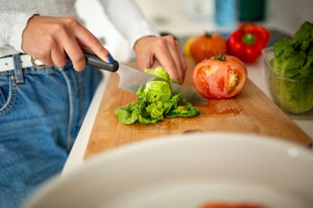 Photo for Close up female hand and knife cutting salad - Royalty Free Image