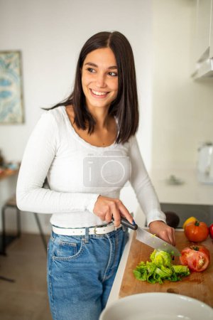 Téléchargez les photos : Portrait jeune femme souriante dans les légumes de coupe de cuisine - en image libre de droit