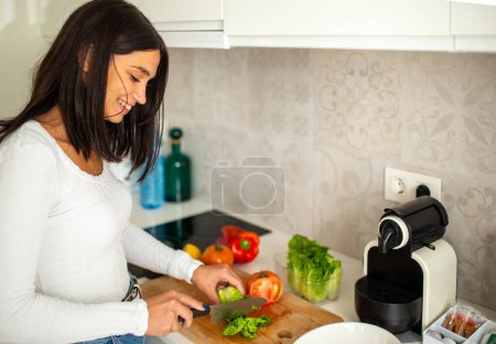 Foto de Retrato sonriente mujer joven cortando verduras en casa cocina - Imagen libre de derechos