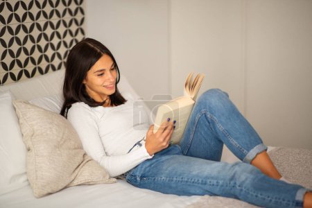 Téléchargez les photos : Portrait jeune femme confortable dans le lit livre de lecture - en image libre de droit