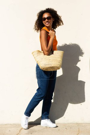 Photo for Full body portrait smiling young woman with bag posing by white wall - Royalty Free Image