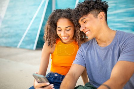 Photo for Portrait of smiling young couple looking at mobile phone together - Royalty Free Image