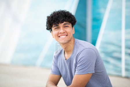 Téléchargez les photos : Portrait jeune homme souriant aux cheveux bouclés - en image libre de droit