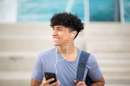 Photo for Portrait cool smiling man with mobile phone and earphones - Royalty Free Image