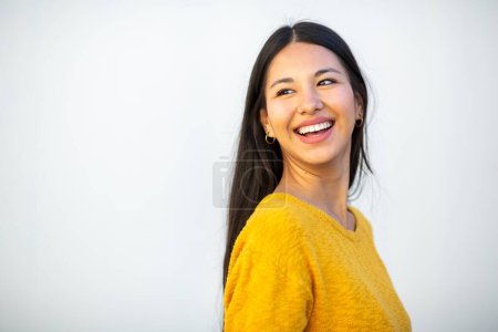 Téléchargez les photos : Portrait latéral jeune femme heureuse par mur blanc - en image libre de droit