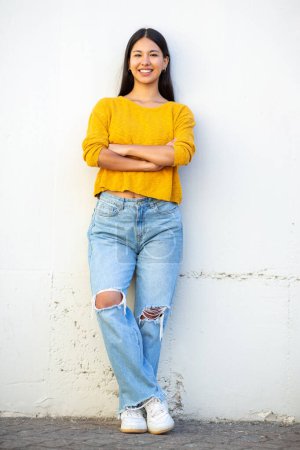 Photo for Full body portrait smiling young woman standing by white wall with arms crossed - Royalty Free Image