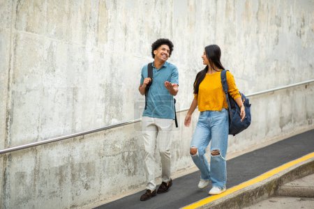 Téléchargez les photos : Portrait complet du corps jeune couple souriant avec des sacs marchant dans la rue - en image libre de droit