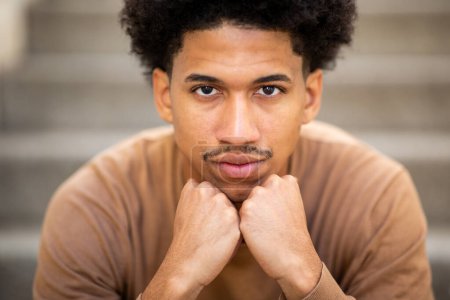 Téléchargez les photos : Gros plan portrait cool jeune homme afro-américain regardant avec les mains sur le menton - en image libre de droit