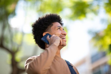 Téléchargez les photos : Gros plan du jeune Afro-Américain riant en parlant sur son téléphone portable - en image libre de droit