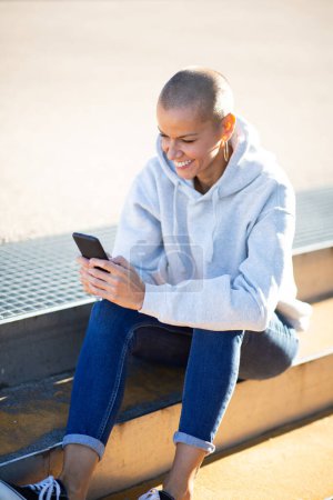 Téléchargez les photos : Portrait de sourire avec les cheveux courts femme regardant le téléphone portable dans les mains - en image libre de droit