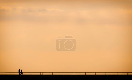 Téléchargez les photos : Couple marchant au coucher du soleil dans un port - en image libre de droit